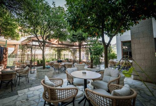 a patio with tables and chairs and trees at Sharm Hotel Luxury in Gjirokastër