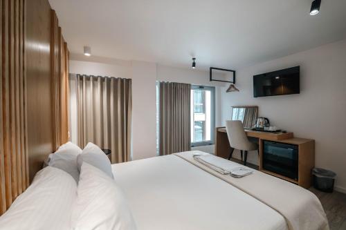 a hotel room with a white bed and a desk at Sharm Hotel Luxury in Gjirokastër