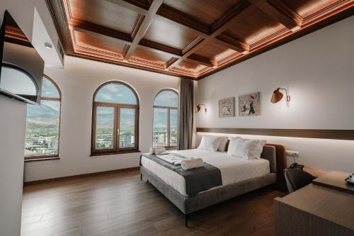 a bedroom with a bed and windows and a couch at Sharm Hotel Luxury in Gjirokastër
