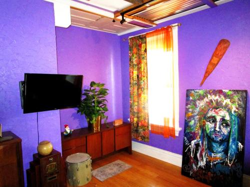 a purple room with a painting of a man at The Bleu Guitar Suite in Saint Louis