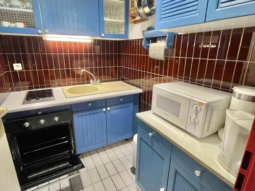 Elle comprend une petite cuisine avec des placards bleus et un four micro-ondes. dans l'établissement Bel Appartement T2 - 5 pers, Ligne 1, Plage, Parking - FR-1-716-23, à La Grande Motte