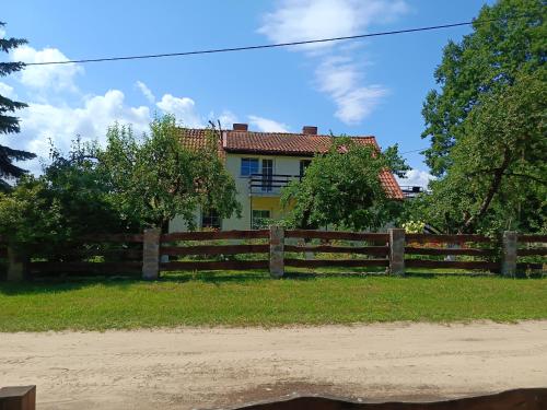 a house behind a wooden fence in front of a field at Gospodarstwo agroturystyczne MARKO , pokoje Guja in Guja