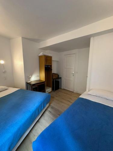 une chambre avec deux lits avec des draps bleus et une pièce dans l'établissement Hotel La Louisiane, à Paris