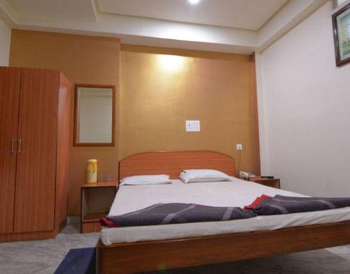 那格浦尔Hotel Parth的卧室里有一张带木质床头板的大床