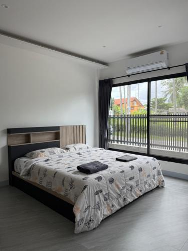 ein Schlafzimmer mit einem Bett und einem großen Fenster in der Unterkunft P One Apartments in Chalong 