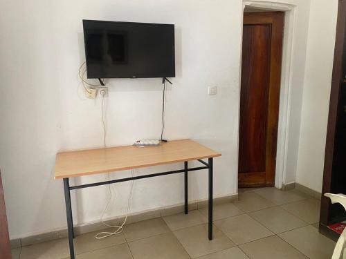 a wooden table with a television on a wall at Pension Les Palmiers in Kipé