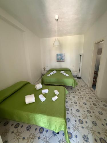 two beds in a room with green sheets and towels at Fantasy House 2.0 in Forio d'Ischia