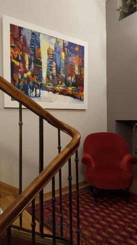a staircase with a red chair and a painting on the wall at Aux Pierres Magiques in Saint-Laurent-de-Chamousset