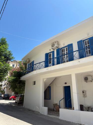 a white building with blue windows and a balcony at Violeta in Agios Kirykos