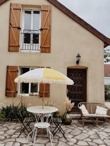 a table with an umbrella in front of a house at Le gîte de Marceau 