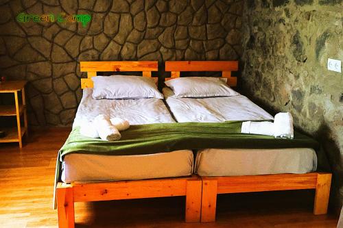 a wooden bed with a green blanket and pillows at Green Camp eco-rural and civil society tourism center in Pokr Ayrum