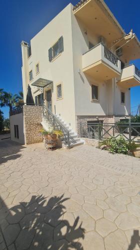 a large white building with stairs and a patio at Aegina Horizon Stonehouse No I in Aegina