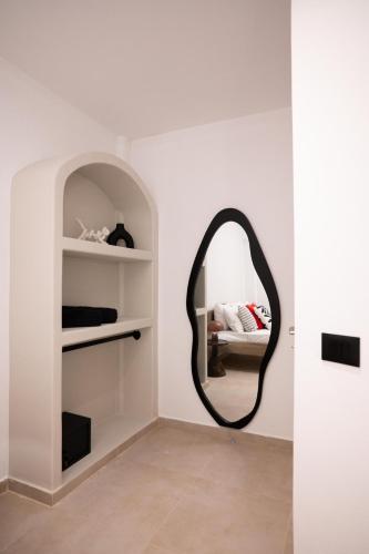 a mirror in a white room with a shelf at AetherOia Suites in Oia