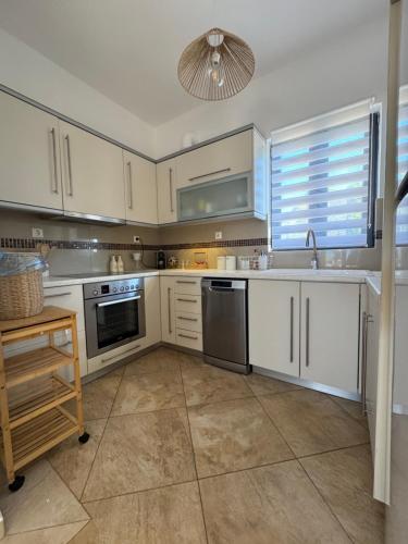 a kitchen with white cabinets and stainless steel appliances at Aegina Horizon Stonehouse No I in Aegina