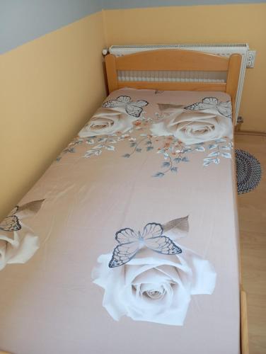 a bed with white sheets and flowers on it at Milica Apartmani in Vrdnik
