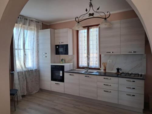 a kitchen with white cabinets and a sink and a stove at Casa da Lilli in Cascina