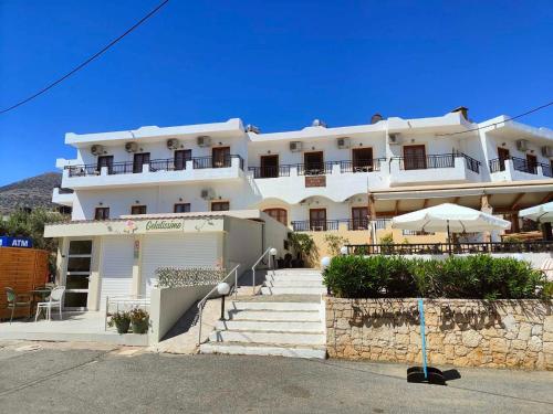 a large white building with stairs in front of it at Diamond Beach Apts & Studios in Stalida