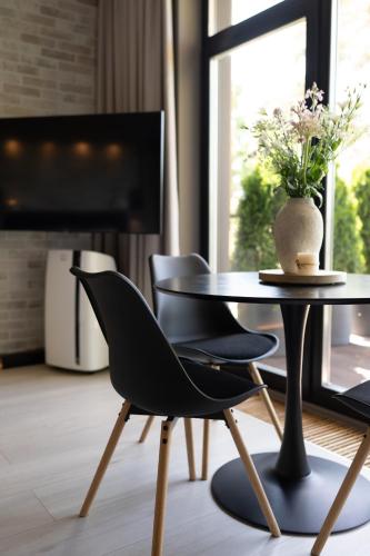 a table and chairs in a living room with a television at SkyGarden Studio - Private Terrace and View in Quiet Jūrmala in Jūrmala