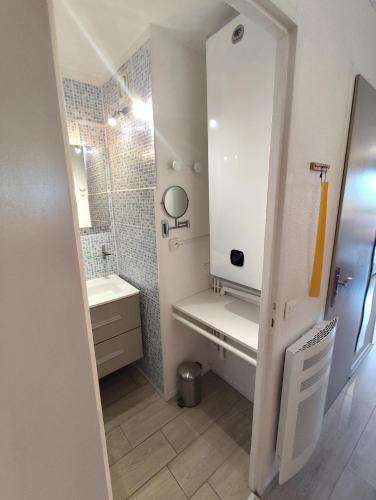 une salle de bain blanche avec un lavabo et un miroir dans l'établissement résidence Plein Sud à côté Jandri express, front de neige, vue splendide, Label 2 Alpes, classé 2 étoiles Tourisme, à Les Deux Alpes
