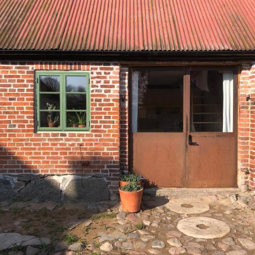 a brick house with a door and a window at Stylish seaside barn in Borrby