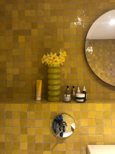 a yellow vase with yellow flowers on a bathroom counter at Stylish seaside barn in Borrby