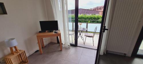 a room with a desk with a television and a balcony at Maison d'Hôtes Sainte Hune Chambres et appartements in Hunawihr