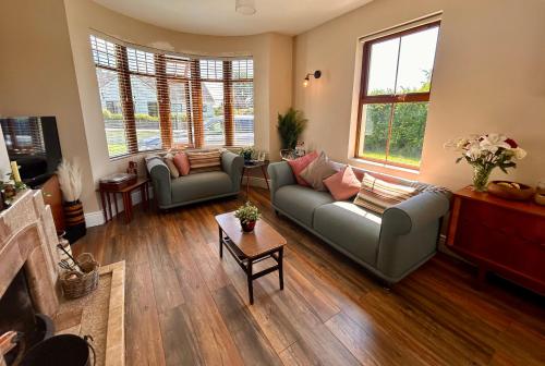 a living room with two couches and two windows at Hillcrest Lodge Townhouse, Carrick-on-Shannon in Carrick on Shannon