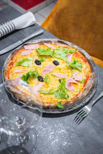 a pizza sitting on top of a table with a fork at Logis Hôtel Vuillot in Cuiseaux