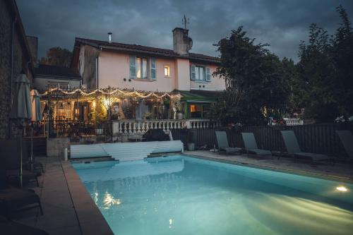 a house with a swimming pool in front of a house at Logis Hôtel Vuillot in Cuiseaux