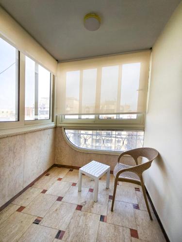 a chair and a table in a room with windows at Afnan Cairo Airport in Cairo