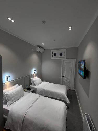 a hotel room with two beds and a flat screen tv at Qadim Hotel in Samarkand