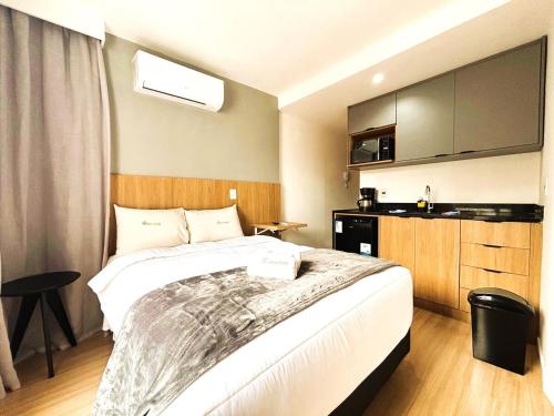 a bedroom with a large bed and a kitchen at UniHome Niterói by Housi in Niterói