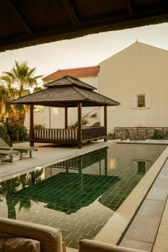a swimming pool with a large umbrella next to a house at Galboka Residence in Nerezine