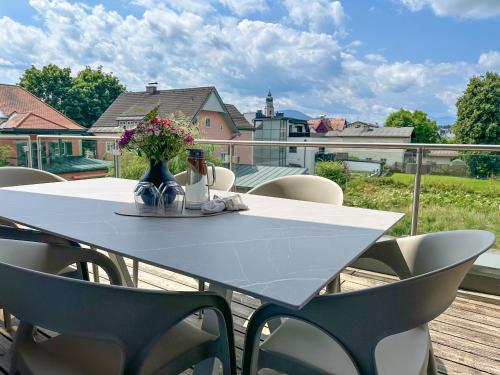 a white table with chairs and a vase of flowers on a balcony at "FIVE" Premium Apartments Seekirchen - exklusive 4-Zi-Penthouse-Wohnung in Seekirchen am Wallersee