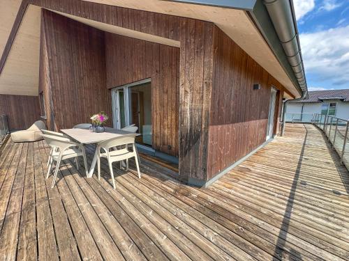 a wooden deck with a table and chairs on it at "FIVE" Premium Apartments Seekirchen - exklusive 4-Zi-Penthouse-Wohnung in Seekirchen am Wallersee
