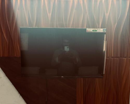 a television screen with a person in front of a curtain at Hotel Radha Madhavam Luxurious Boutique Stay in Mathura