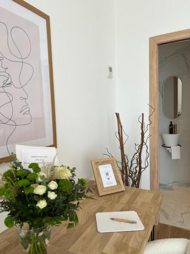 a table with a vase of flowers and a picture at Le Domaine de la Vallée in Vernon