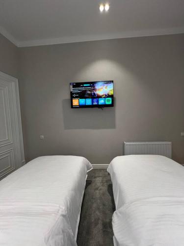 two beds in a room with a tv on the wall at Qadim Hotel in Samarkand