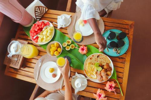 a wooden table with breakfast foods on it at Binta Boutique Hotel - Small Oasis near Nungwi Beach in Nungwi