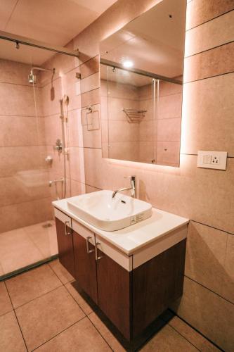 a bathroom with a sink and a shower and a mirror at Nigara Residency in Vandanmedu