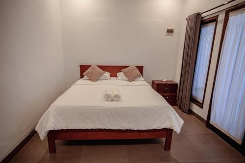 a bedroom with a bed with two wedding shoes on it at Kalamoana House in Gili Trawangan