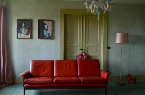 a living room with a red couch and a lamp at Stylish Swedish farmhouse in Borrby