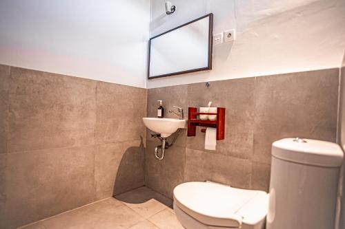 a bathroom with a sink and a toilet and a mirror at Kalamoana House in Gili Trawangan