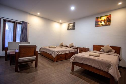 a bedroom with two beds and a desk and a chair at Kalamoana House in Gili Trawangan