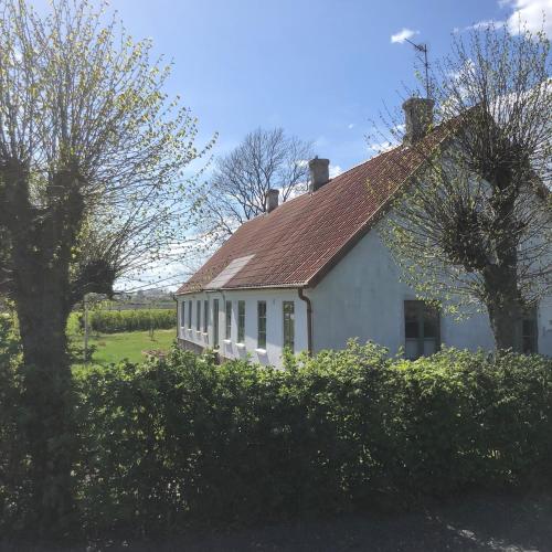 a white house with a red roof and some bushes at Stylish Swedish farmhouse in Borrby