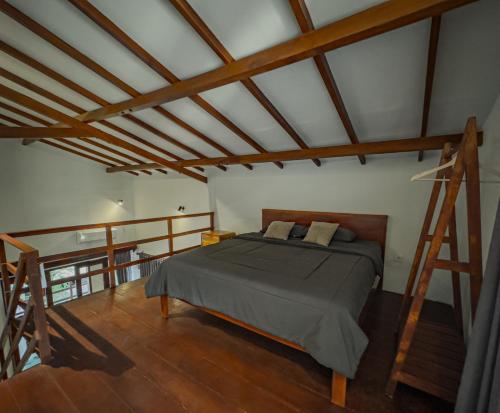a bedroom with a bed in a room with wooden beams at Kalamoana House in Gili Trawangan
