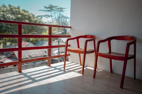 two red chairs sitting on a balcony with a window at Kalamoana House in Gili Trawangan