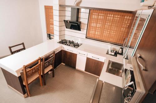 a small kitchen with a white counter top and wooden cabinets at Nigara Residency in Vandanmedu