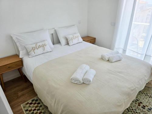 Un dormitorio con una gran cama blanca con toallas. en Alojamento Xaandar Beach Spot, en Nazaré