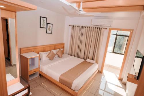 a bedroom with a bed and a tv in it at Nigara Residency in Vandanmedu